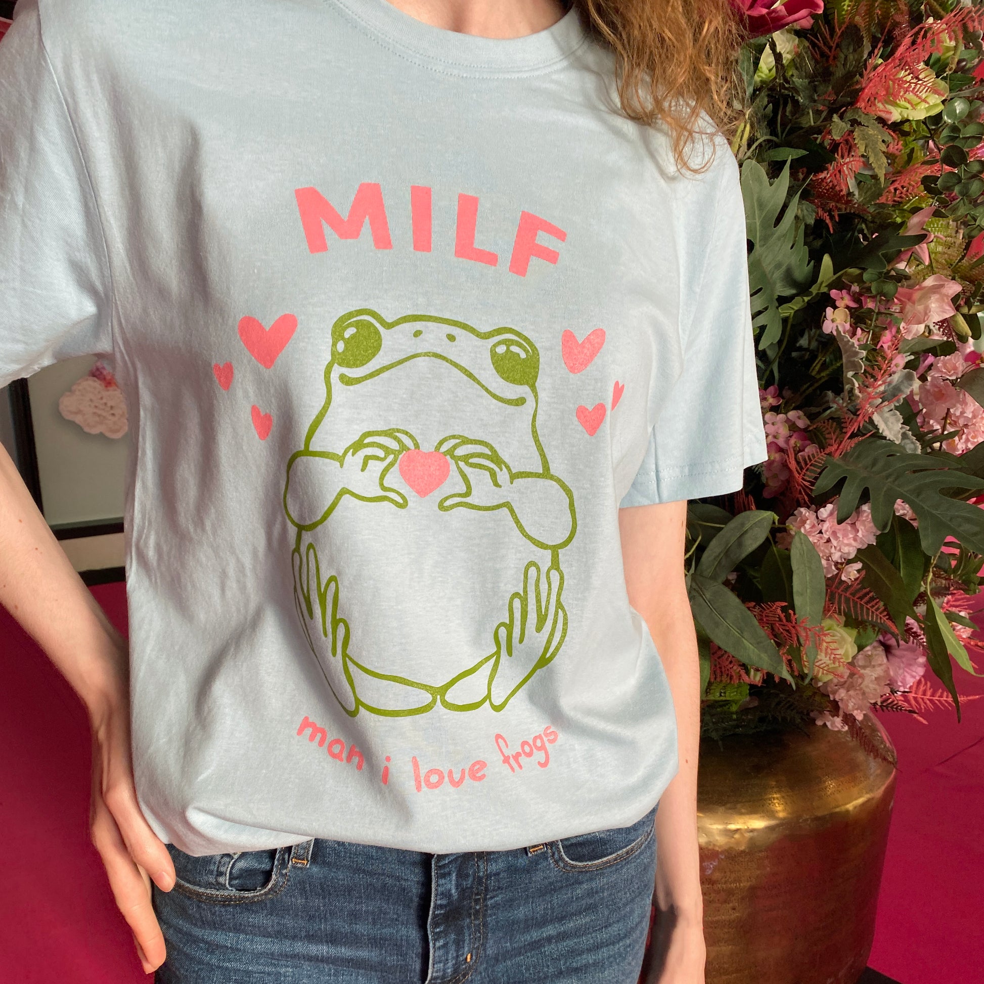 blue t-shirt with a frog screenrpint on it holding a heart in his hands with the text MILF above it. Below it the text says man i love frogs